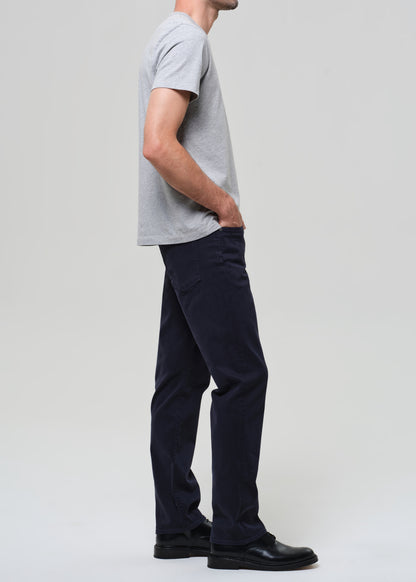 Person wearing a gray t-shirt and dark navy pants on a grey background