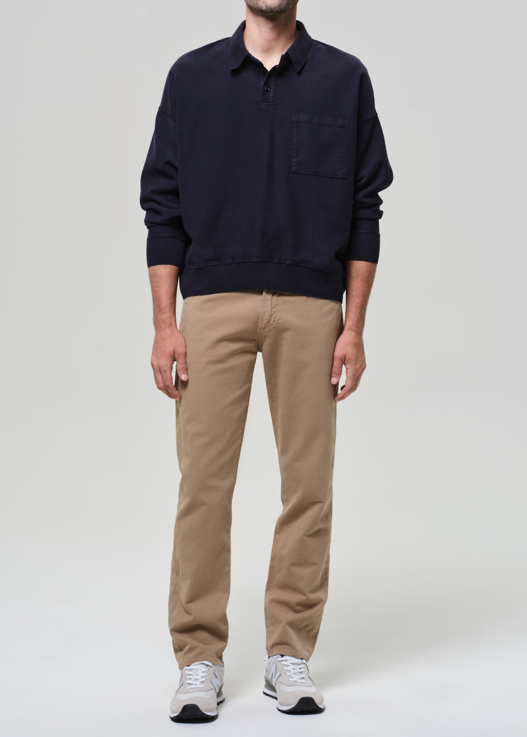 Person wearing a navy sweater and beige pants on a plain background