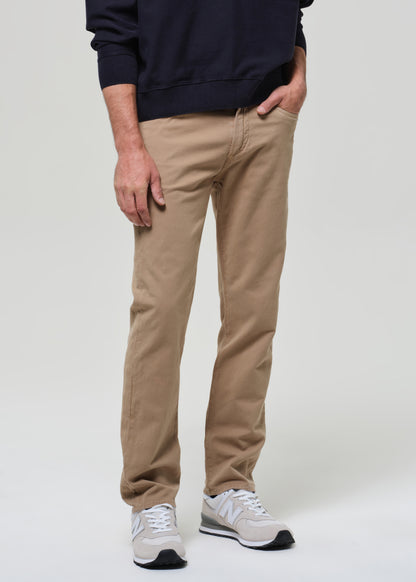 Person wearing a navy sweater and beige pants on a plain background