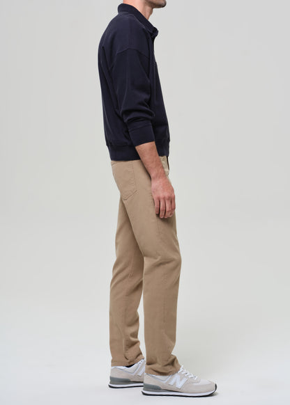 Person wearing a navy sweater and beige pants on a plain background
