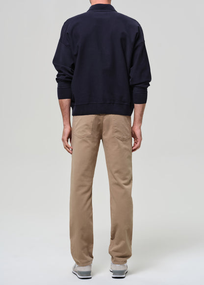 Person wearing a navy sweater and beige pants on a plain background