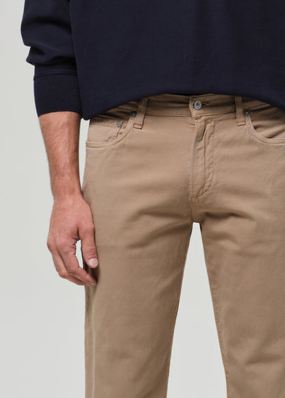Person wearing a navy sweater and beige pants on a plain background