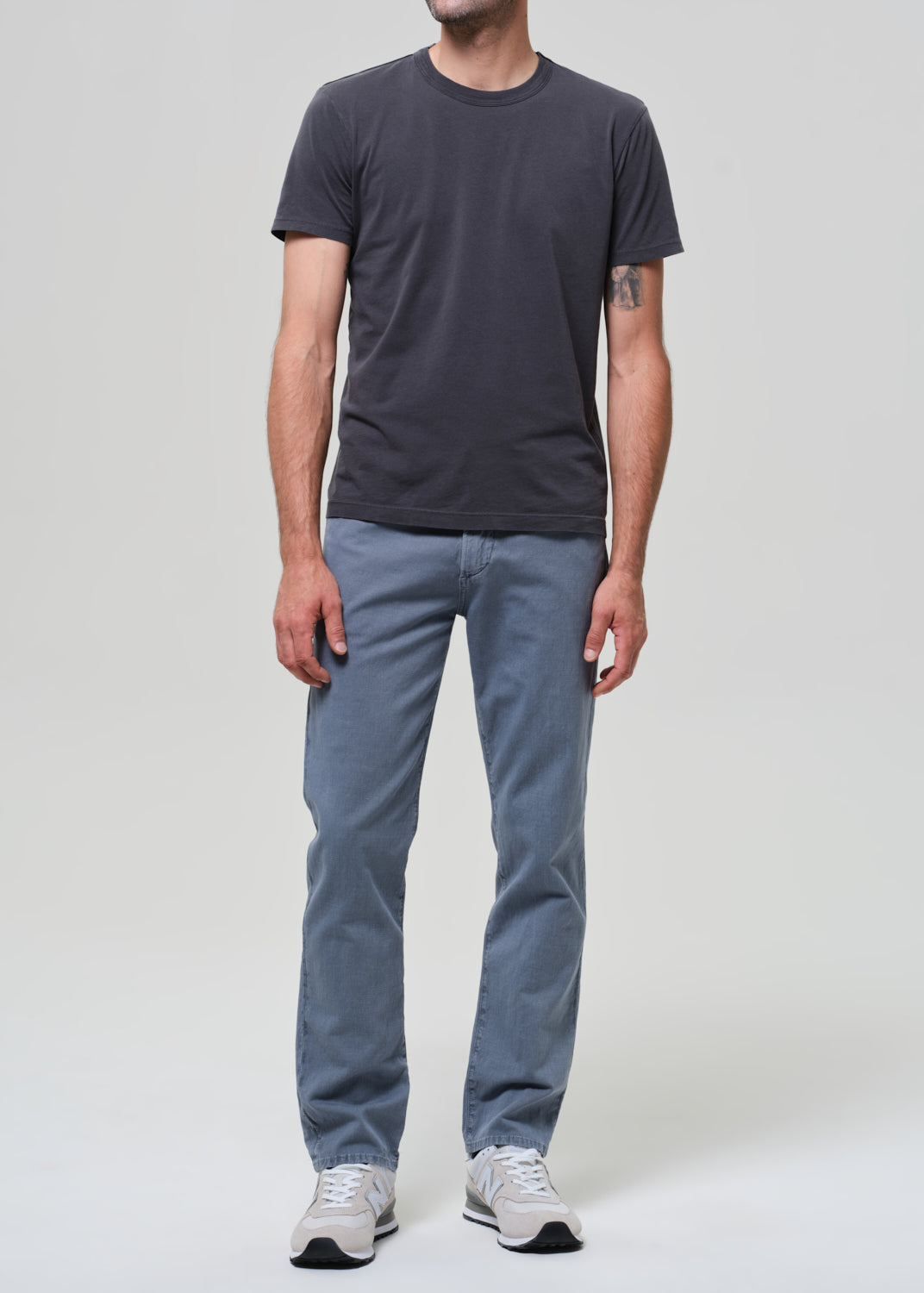 Person wearing a dark gray t-shirt and blue pants on a plain background