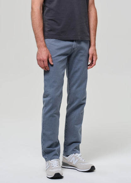 Person wearing a dark gray t-shirt and blue pants on a plain background