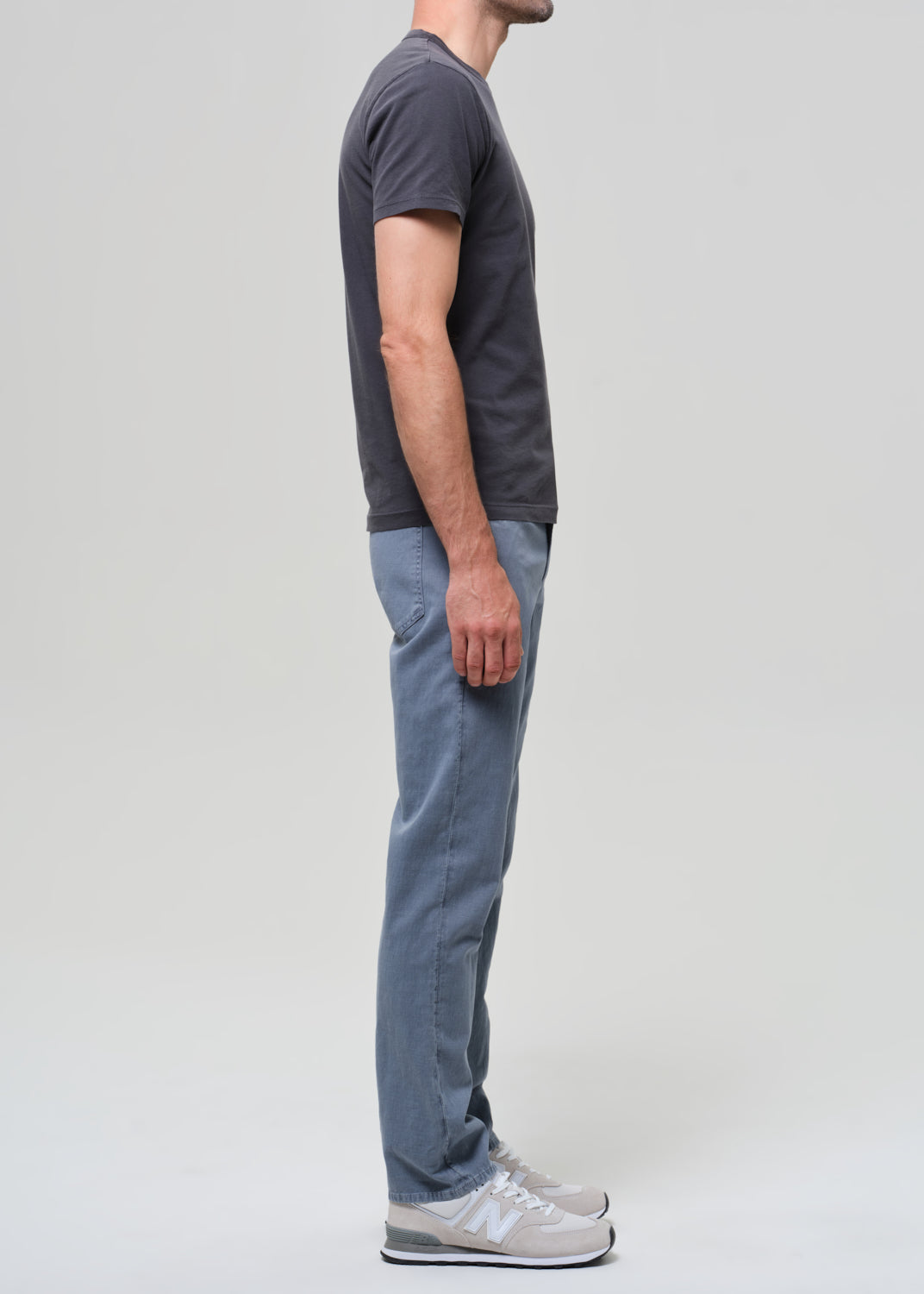 Person wearing a dark gray t-shirt and blue pants on a plain background