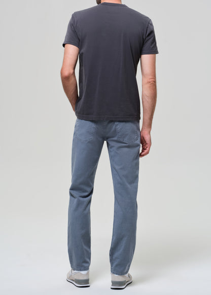 Person wearing a dark gray t-shirt and blue pants on a plain background