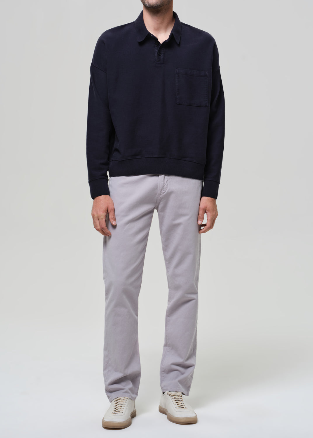 Person wearing a navy poly and light gray pants on a plain background