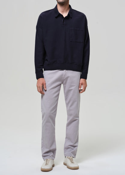 Person wearing a navy poly and light gray pants on a plain background