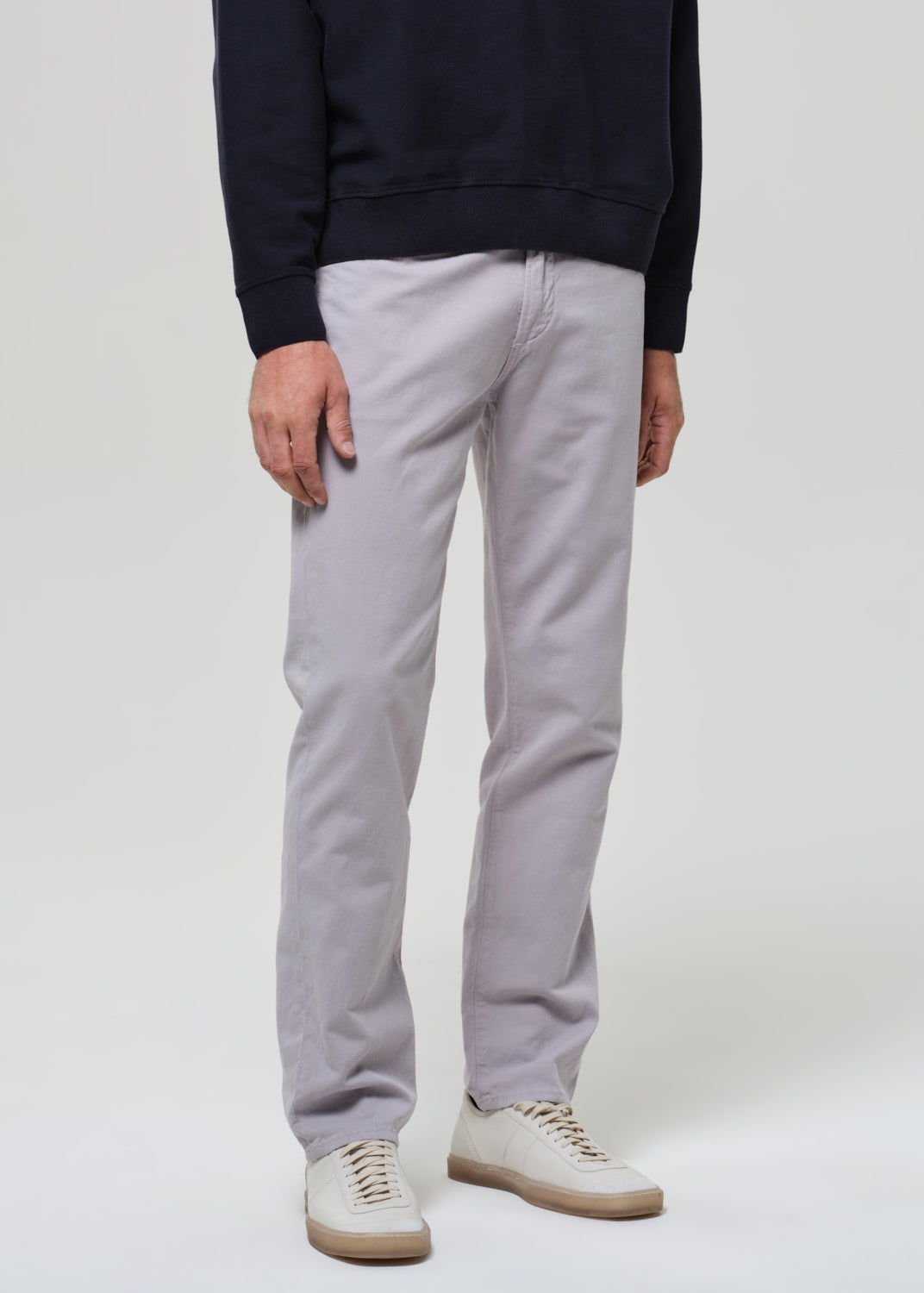 Person wearing a navy poly and light gray pants on a plain background