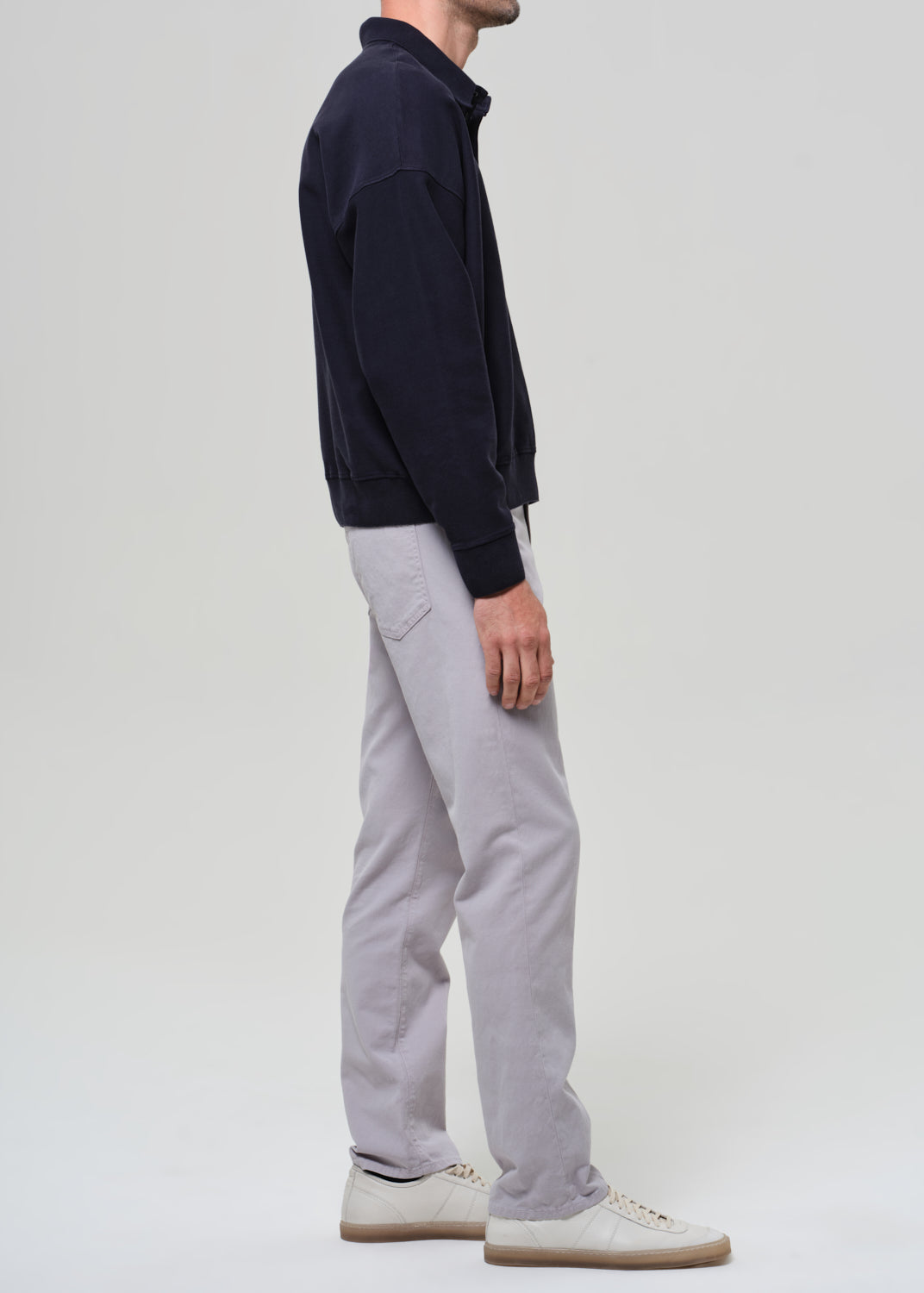 Person wearing a navy poly and light gray pants on a plain background