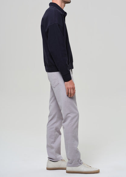 Person wearing a navy poly and light gray pants on a plain background