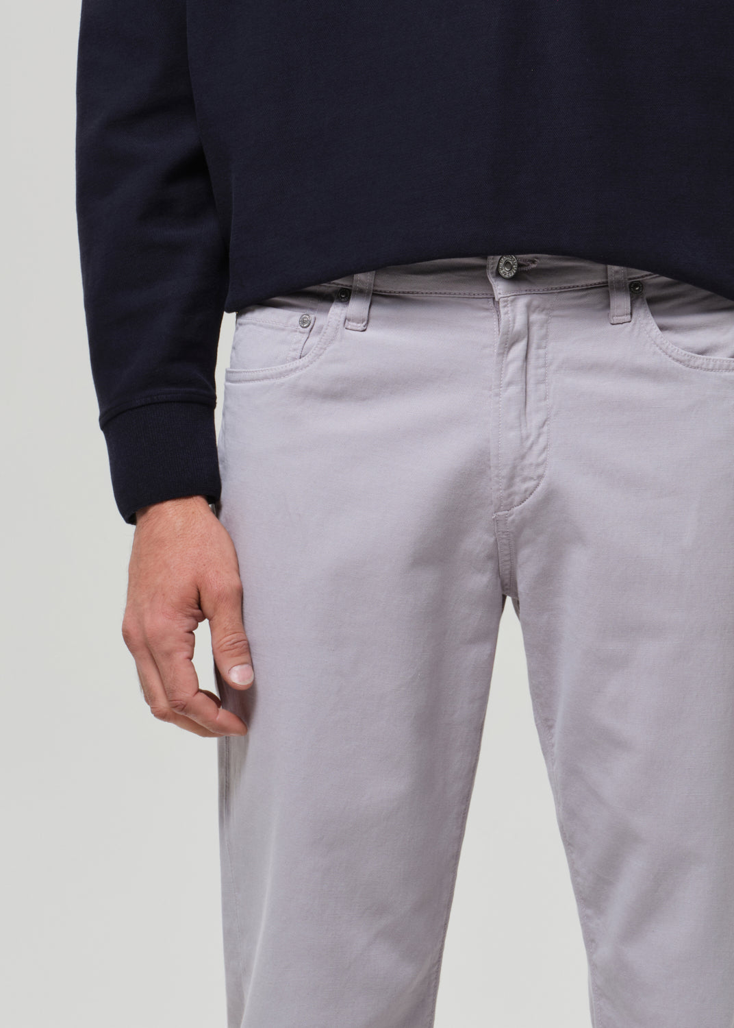 Person wearing a navy poly and light gray pants on a plain background