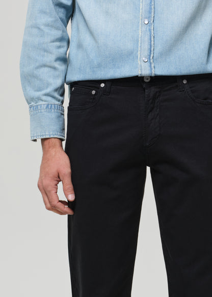 Person wearing a light blue denim shirt and black pants on a plain background