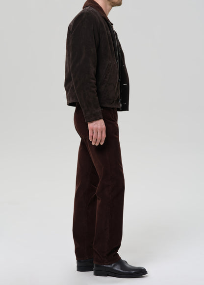 Person wearing a brown jacket and pants on a grey background