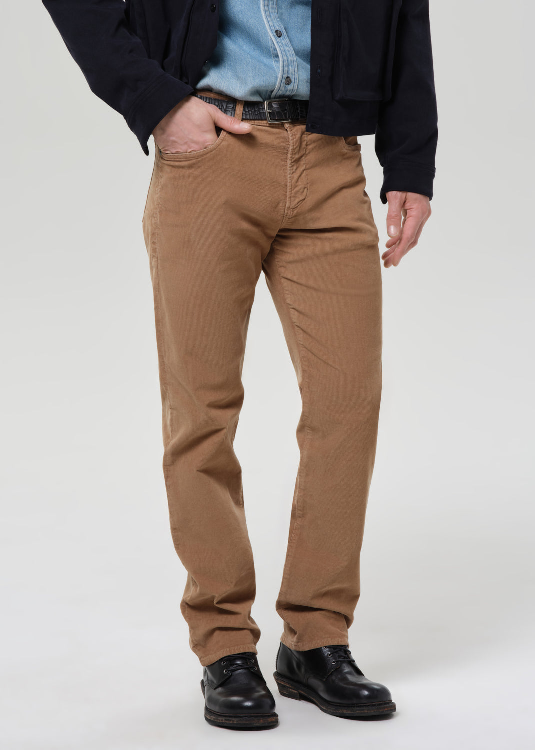 Person wearing brown pants with a grey background