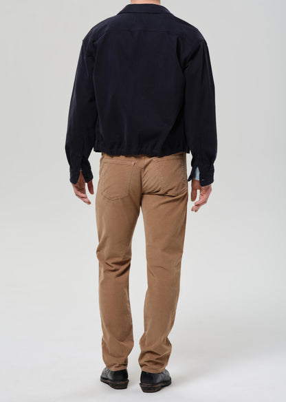 Person wearing a black jacket and tan pants on a grey background