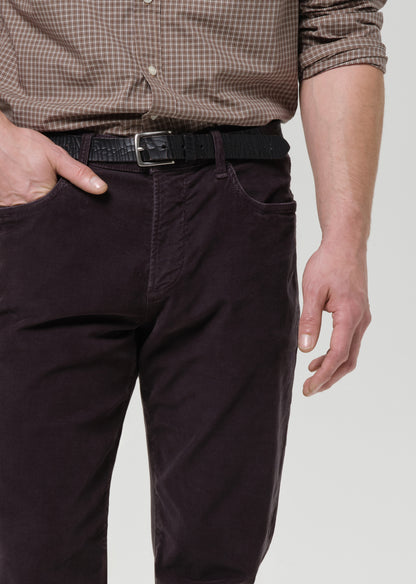 Person wearing a brown checkered shirt and dark grey pants on a grey background