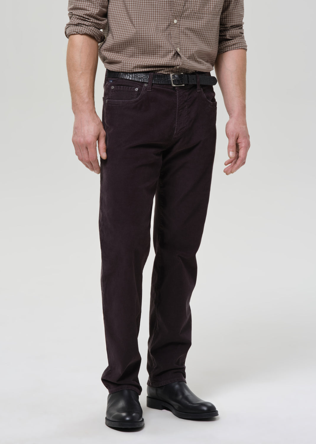 Person wearing dark grey pants and a patterned shirt on a grey background
