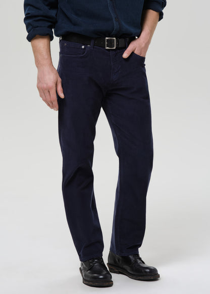 Person wearing navy blue pants and black shoes on a grey background