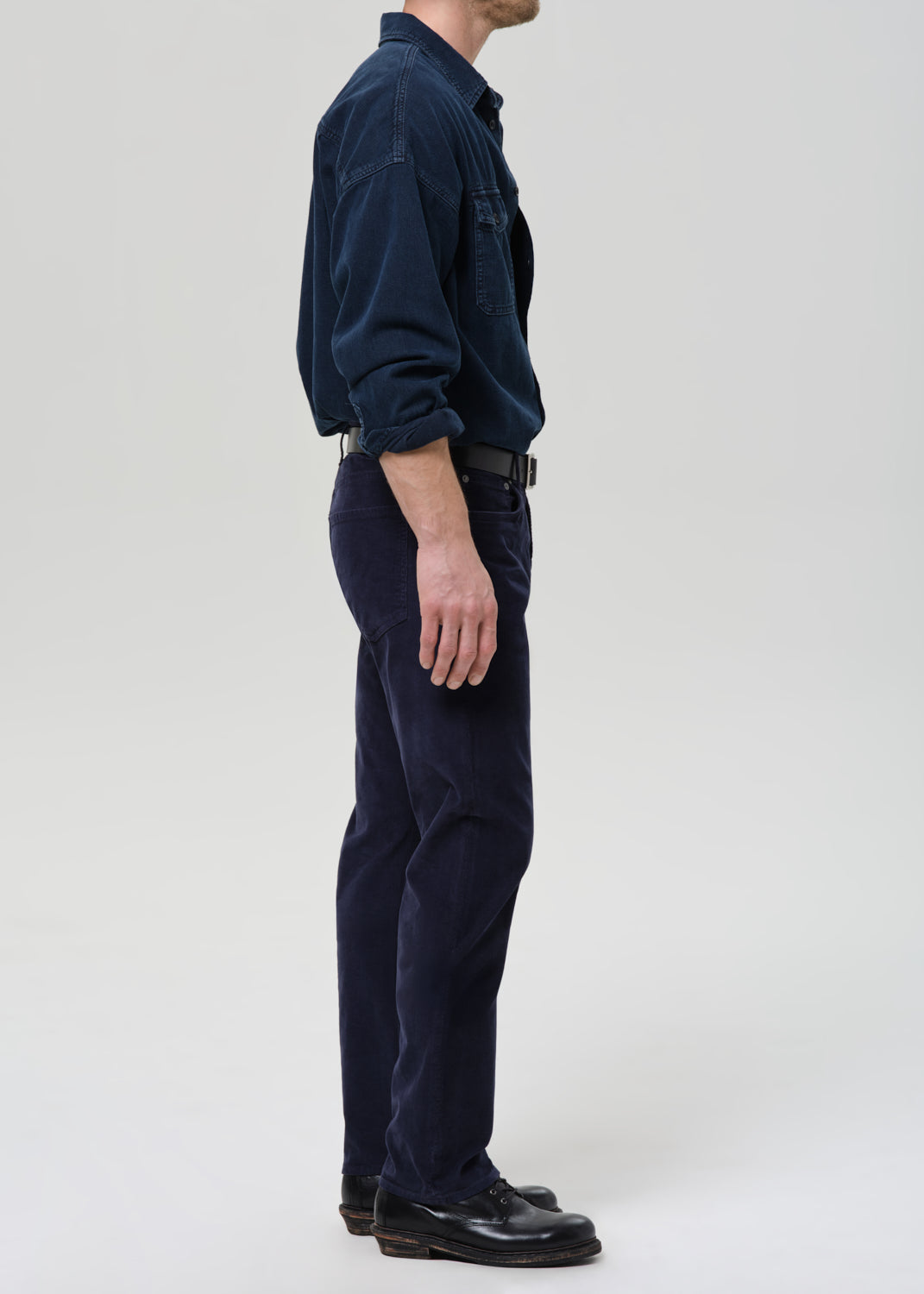 Person wearing a navy blue shirt and pants on a grey background