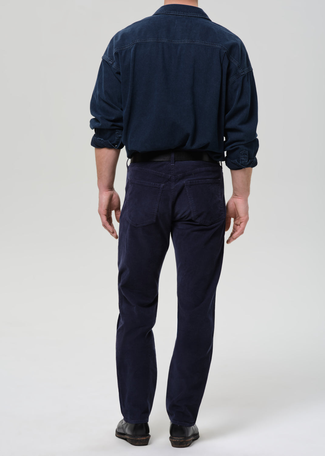 Person wearing a navy blue shirt and pants on a grey background