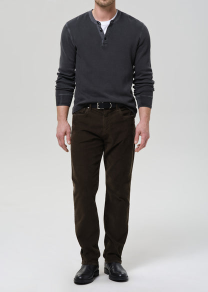 Man wearing a dark gray long-sleeve shirt and brown pants on a grey background