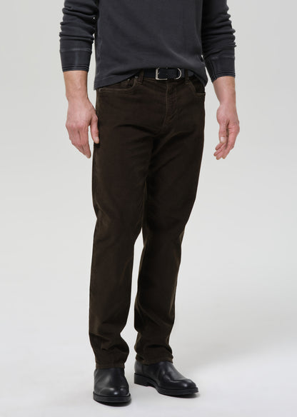Person wearing dark brown pants and black shoes on a grey background
