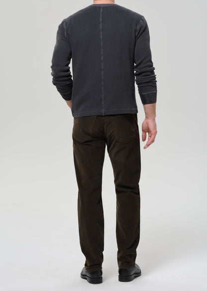 Person wearing a dark gray long-sleeve shirt and brown pants on a grey background