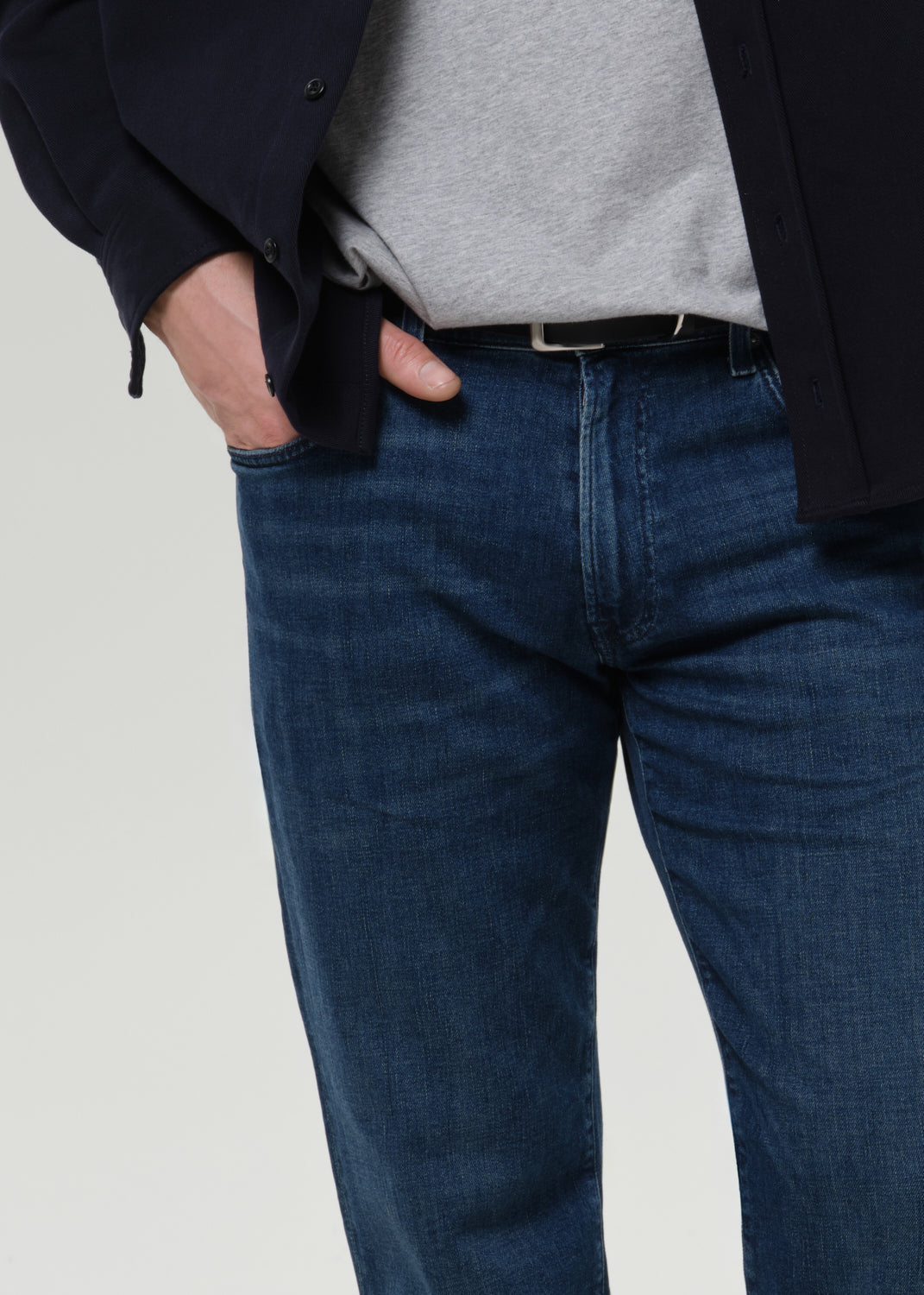 Close-up of medium blue straight leg jeans on a grey background.