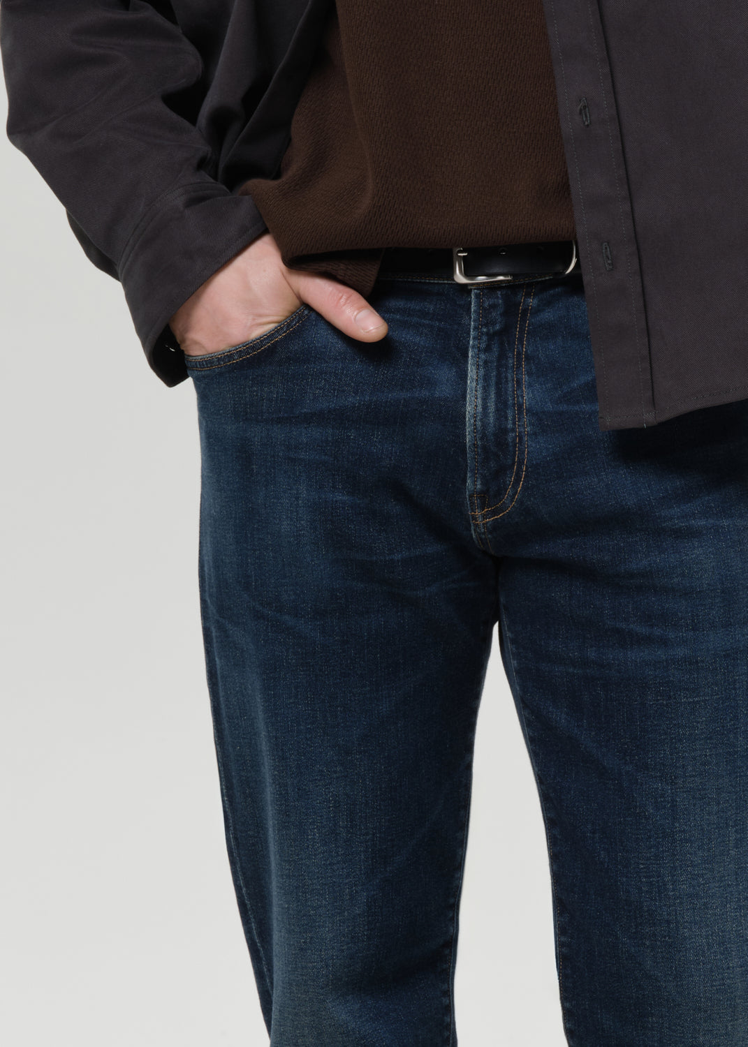 Close-up of dark indigo straight leg jeans on a grey background.