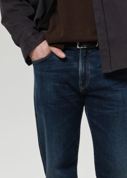 Close-up of dark indigo straight leg jeans on a grey background.
