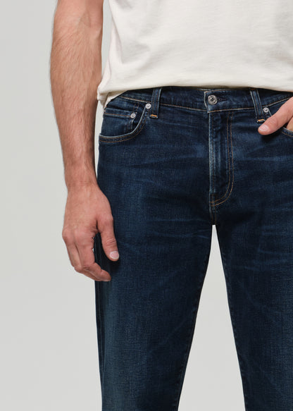 Person wearing dark blue jeans and a white shirt on a light gray background
