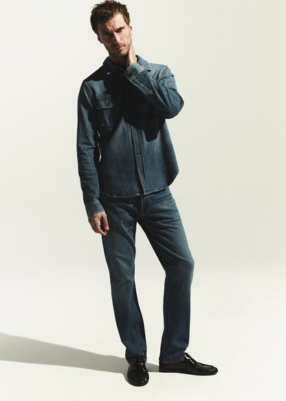 Man wearing a denim shirt and jeans on a white background