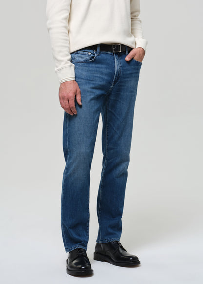 Person wearing blue jeans and a white sweater on a plain background