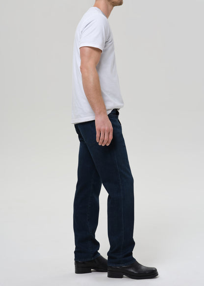 Person wearing a white t-shirt and dark jeans on a plain background