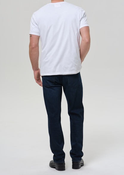 Person wearing a white t-shirt and dark jeans on a plain background