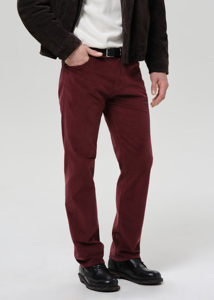 Person wearing maroon pants with a grey background