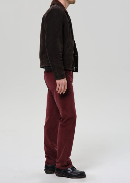 Person wearing a brown jacket and red pants on a grey background