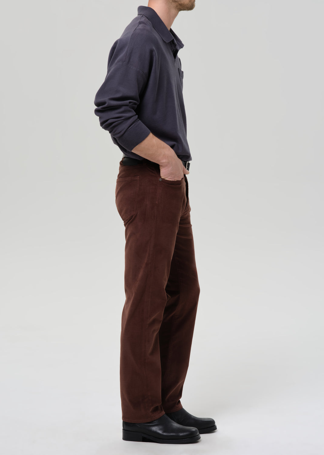 Person wearing a dark shirt and brown pants on a grey background