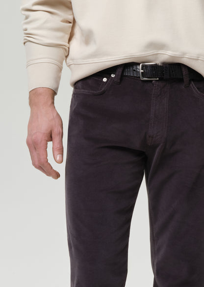 Person wearing dark pants and a beige sweater on a grey background
