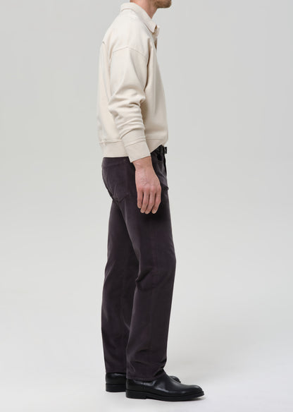 Person wearing a cream sweater and dark pants on a grey background