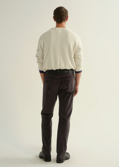 Person wearing dark charcoal straight leg jeans with a cream long sleeve shirt and black boots, back full body view on a light grey background.