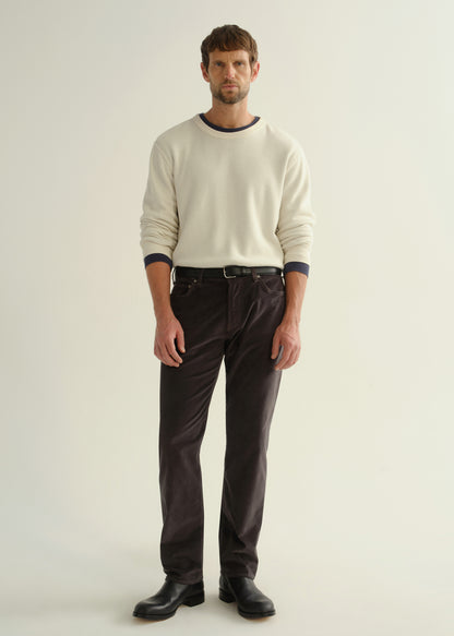 Person wearing dark charcoal straight leg jeans with a cream long sleeve shirt and black boots, front full body view on a light grey background.