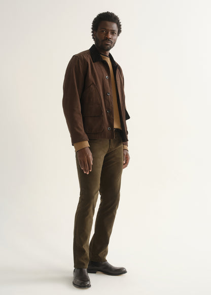 Person wearing dark brown straight leg pants with a brown jacket, dark shirt, and black shoes, angled front full body view on a light grey background.