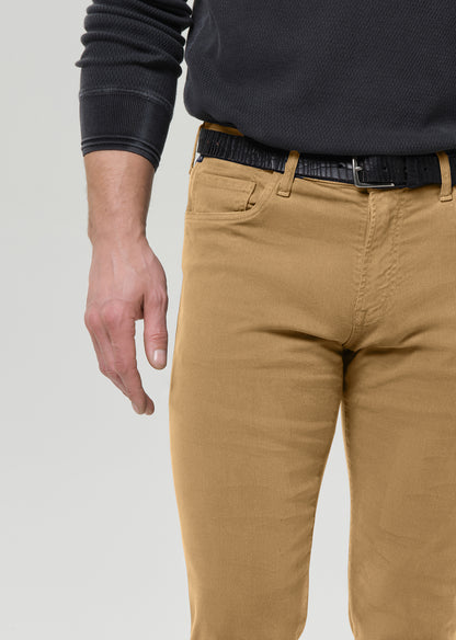 A close-up of a person wearing tan chinos with a black textured belt and a dark charcoal ribbed sweater, cropped from the chest down against a light grey background.