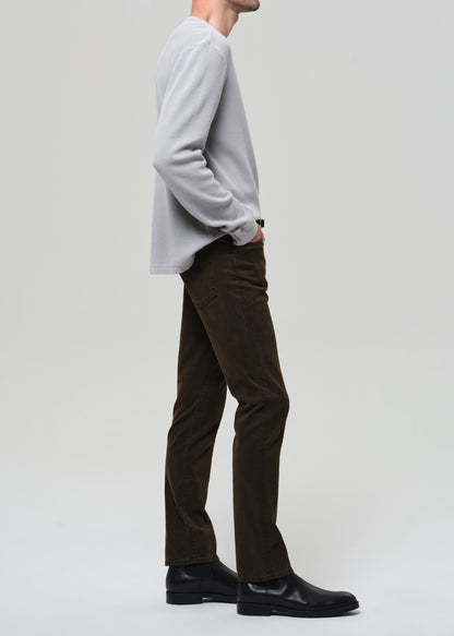 Person wearing brown pants and black shoes on a plain background