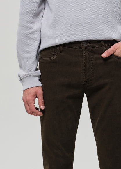 Person wearing brown pants and a light gray sweater on a plain background