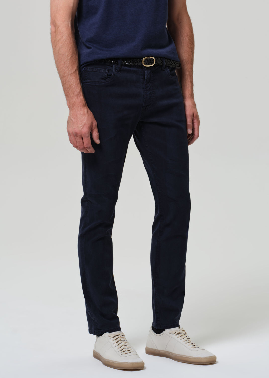 Person wearing navy blue jeans and a dark shirt on a plain background