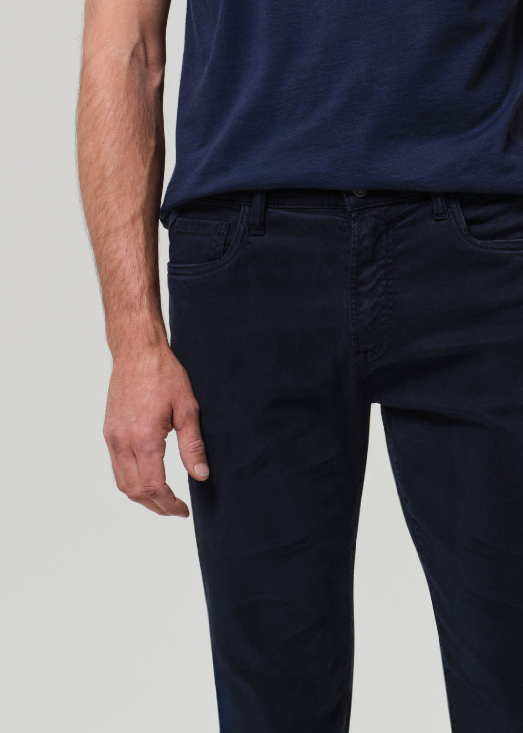 Person wearing navy blue pants and shirt on a light gray background