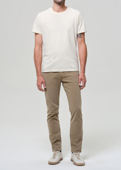 Man wearing a white t-shirt and beige pants on a plain background